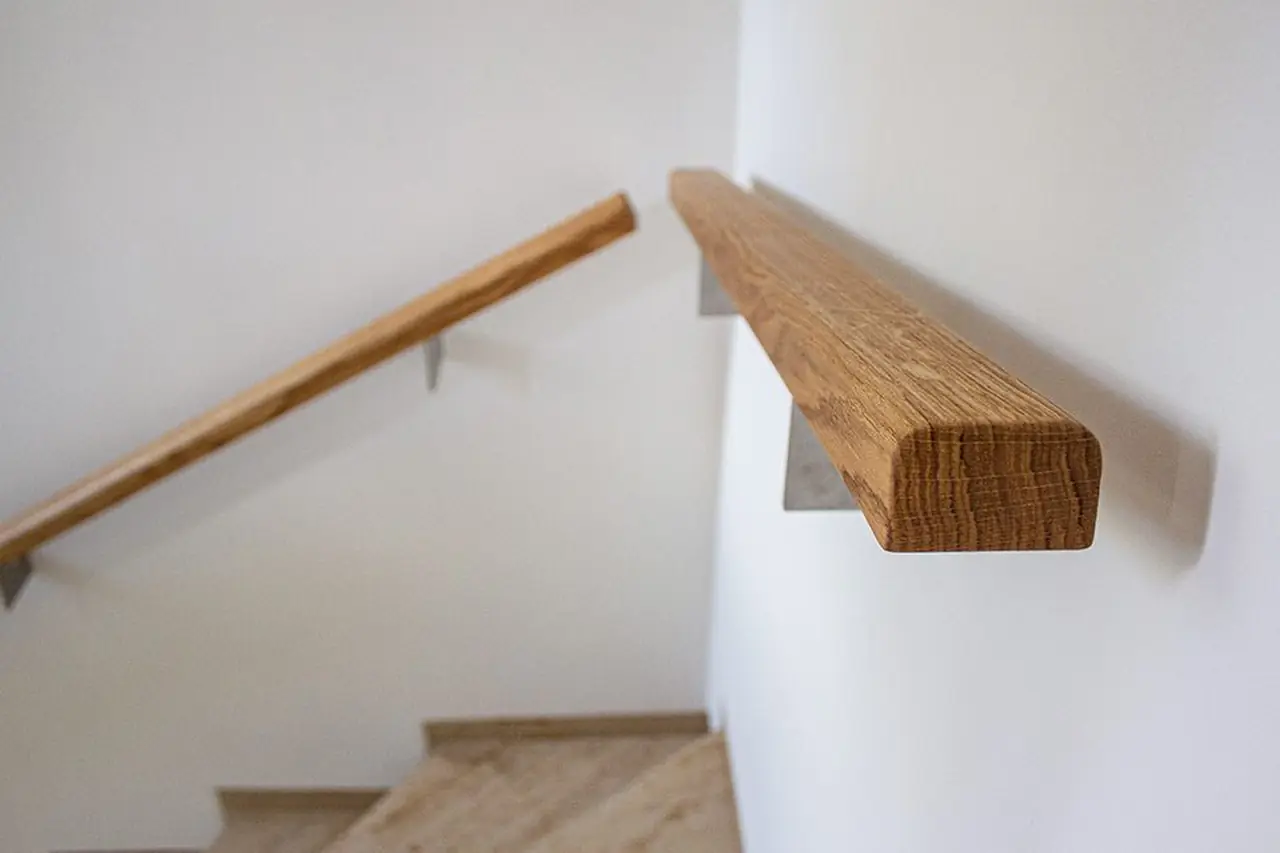 Detailaufnahme eines massiven Eichenhandlaufs mit Wandhalterung