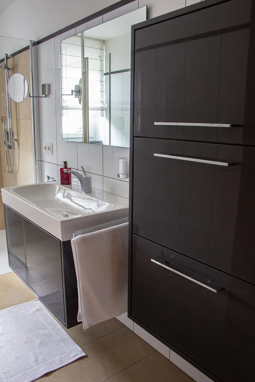 Badezimmer mit Hochschrank mit Auszügen und Edelstahlgriffen nach Maß